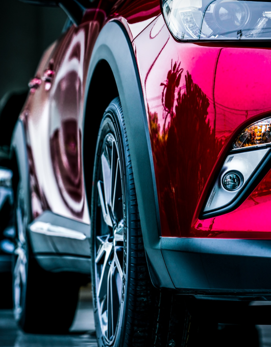 Imagem da parte inferior esquerdo de um carro vermelho.